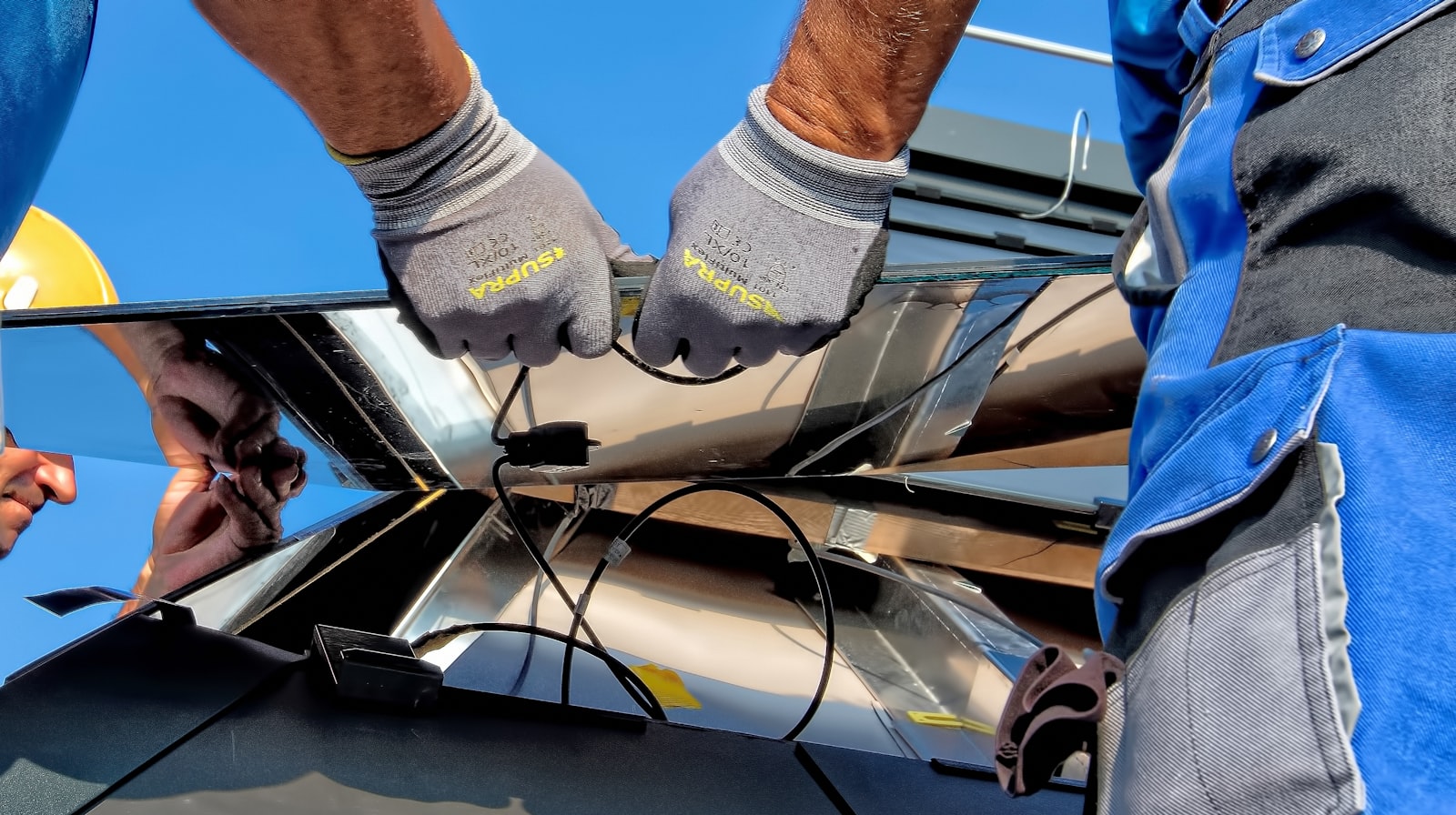 Technicians' hands fastening a solar panel during installation